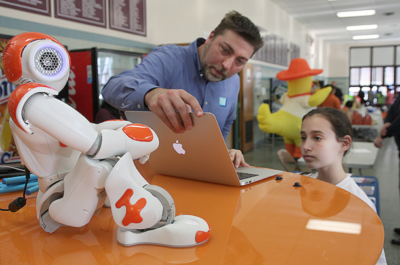 Teacher with Student using a Macbook and Teaching Assistant Robot