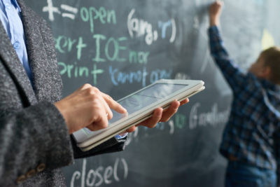 Teacher Referencing Data While Student Writes on the Board