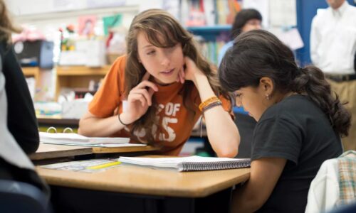 A teacher helps a student in class.